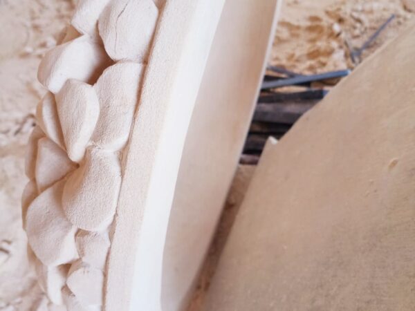 Frangipanirelief Seitliche Abbildung des runden Steinreliefs, auf dem Wölbung und ausgehöhlte Rückseite zu erkennen sind